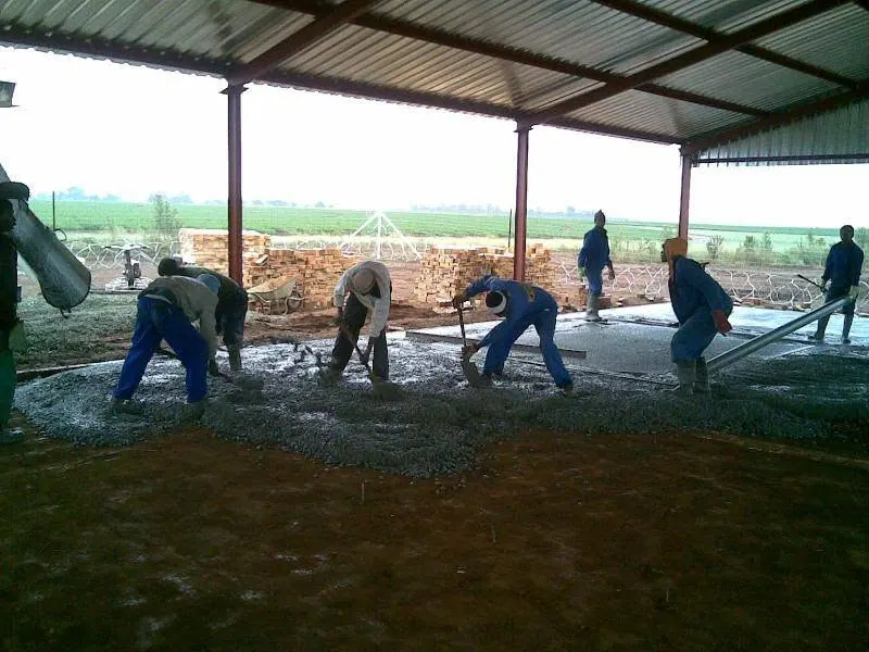 Team pouring a concrete slab under a roof structure
